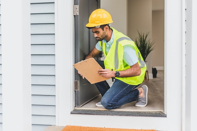 inspector-wearing-hard-hat-inspecting-door-frames-of-rental-property