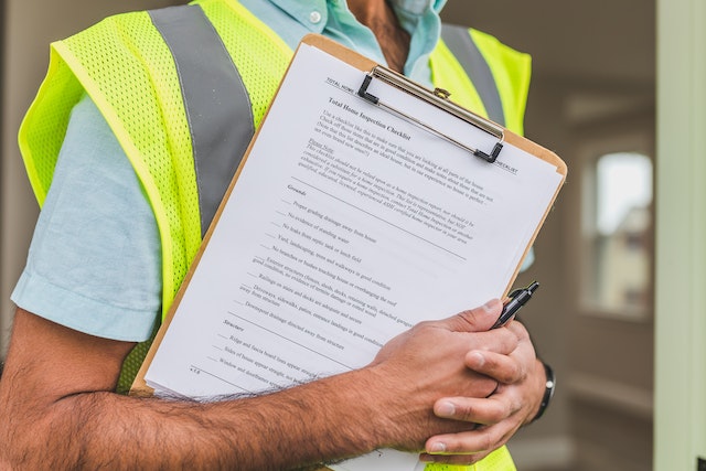 a-person-in-a-safety-vest-holding-a-clipboard-with-documents