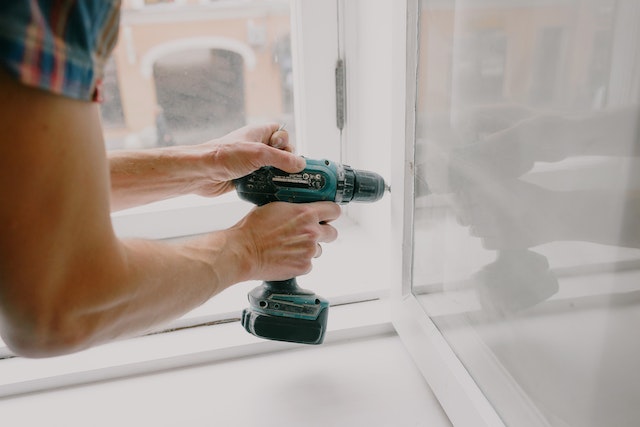a-person-using-an-electric-drill-to-fix-a-window